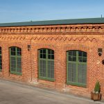 A charming red brick building with green windows in Jönköping, Sweden, under clear blue skies.